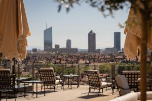 a patio with tables and chairs and a view of the city at Villa Florentine, A Beauvallon Hotel & Spa in Lyon