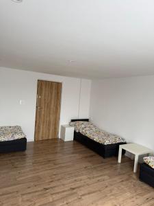 a room with two beds and a table and a door at Agroturystka Nowotny in Zawada Książęca
