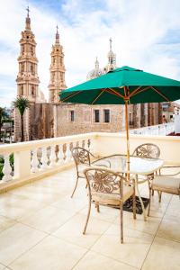a table and chairs with an umbrella on a balcony at Hotel Fiesta Alteña in Tepatitlán de Morelos
