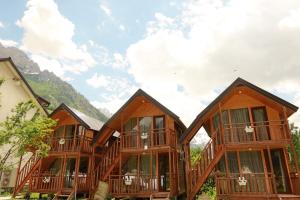 a row of wooden houses with mountains in the background at BUJTINA IZET SELIMAj in Valbonë