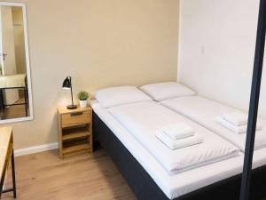 a bedroom with a bed with white sheets and a mirror at Klaksvik Mountain View Stay in Klaksvík