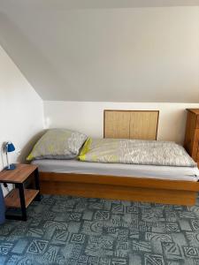a bedroom with a bed with a wooden headboard and a table at Chata na Špince in Červený Kostelec