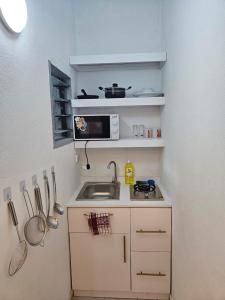 a small kitchen with a sink and a microwave at 1e Studio Moderne au cœur de Cocody 7e tranche- Tout inclus in Cocody +7 photos