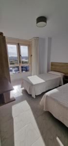 a bedroom with two beds and a large window at Apartamentos Regollera in Noja +104 photos