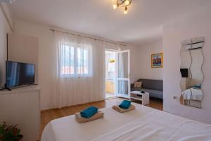 a room with a bed and a tv and a couch at Lumina Apartments in Korčula
