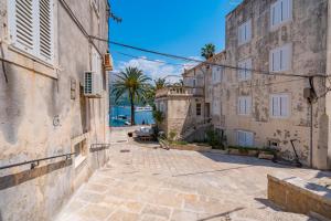 an alley in an old town with buildings and palm trees at Lumina Apartments in Korčula