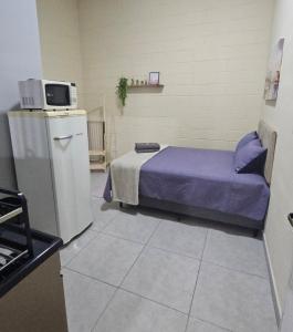 a room with a bed and a small refrigerator at Kitnet Completa em Cotia com Garagem 04 in Cotia
