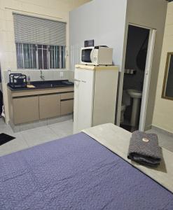 a room with a kitchen with a bed and a microwave at Kitnet Completa em Cotia com Garagem 04 in Cotia