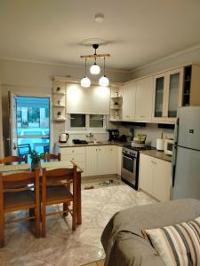 a kitchen with white cabinets and a table and a dining room at Captain's House in Filiatra