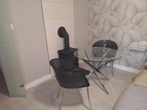 a glass table and two chairs in a room at Domek Za Wyspą 3 in Chmielów