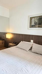 a bedroom with a large white bed with a wooden wall at Flat Niagara Belo Horizonte in Belo Horizonte +18 photos
