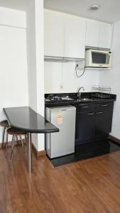 a kitchen with a table and a sink and a stove at Flat Niagara Belo Horizonte in Belo Horizonte