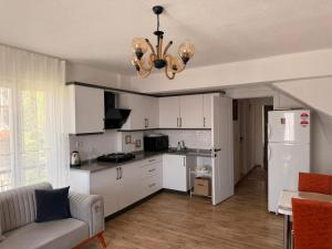 a kitchen with white cabinets and a white refrigerator at Olivra Apart in Cedit