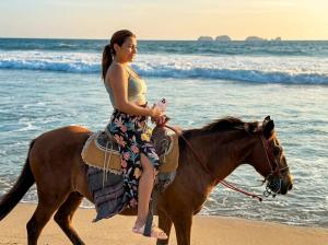 a woman riding a horse on the beach at Residences at Las Palmas in Zihuatanejo