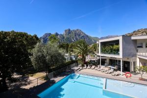 a villa with a swimming pool and mountains in the background at Camping Al Porto - Mini Glamping & Mobile Homes in Nago-Torbole