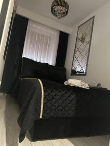 a black bed with a black comforter and a window at Imperial Apartament in Gniezno