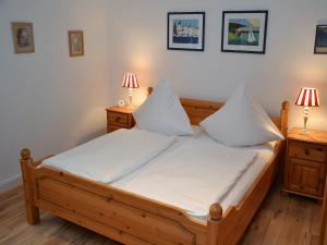 a bedroom with a bed with white sheets and two lamps at Haus Seeflieger in Westerland