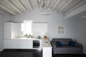 a kitchen with white cabinets and a couch in a room at Casa Matteotti in Modica