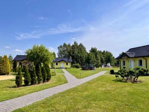 a walkway in a park with houses and trees at Brzozowy Zakątek in Dąbki