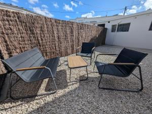 three chairs and a table in front of a fence at Studio cosy - terrasse privative - lit queen size in Berck-sur-Mer