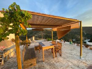 a wooden table and chairs under a wooden pergola at Evnomia Cycladic Home from 1912 in Mélanes