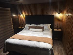 a bedroom with a large bed with two night stands at Mary y Luis in Coihaique
