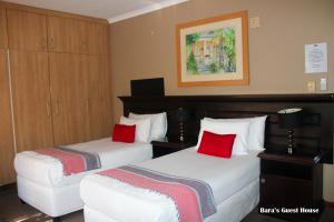 two beds with red pillows in a hotel room at Bara Guesthouse in Welkom +63 photos