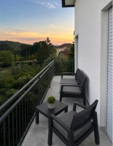 two chairs and a table on a balcony with a sunset at Panorama Krizevac in Međugorje