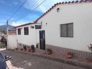 a white house with a door and potted plants at Hostal familiar Shambala in Silos
