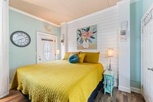 a bedroom with a yellow bed with a clock on the wall at The Poolside Studio - Lounge Pool Wifi in Jacksonville