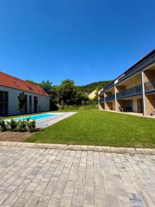 a courtyard with a lawn next to a building at Vinopool Suites Badacsony in Badacsonytomaj