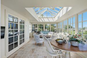 a conservatory with a table and chairs and windows at Dart View Cottage - A Stunning Riverside Escape in the Heart of South Devon in Dittisham