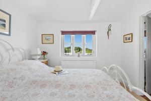 a white bedroom with a bed with a hat on it at Dart View Cottage - A Stunning Riverside Escape in the Heart of South Devon in Dittisham +39 photos