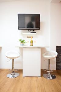 two white stools in a room with a tv on a wall at Starview by MD apartments in Ljubljana