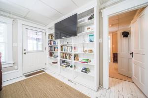 a library with white shelves and a flat screen tv at The Berlin Guesthouse in Millersburg