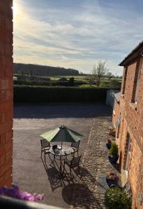 a patio with a table and a green umbrella at Stylish Countryside Loft near Silverstone-Bicester in Buckingham
