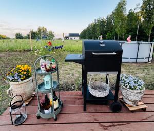 a barbecue grill sitting on a deck with flowers at Chatka u Radka in Szczodrowo