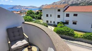 a chair on a balcony with a view of a building at Apartments Grozdana in Baška