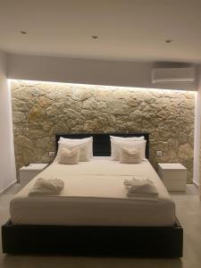 a bedroom with a large bed with a stone wall at Luciano Rooms in Ksamil +60 photos