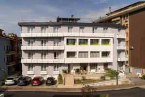 a white building with cars parked in a parking lot at Hotel Palladio in Caorle
