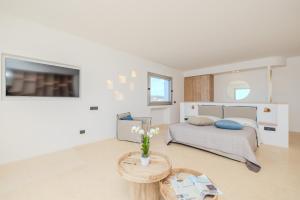a white bedroom with a bed and a table at Antares Rooms and Suites in Olbia