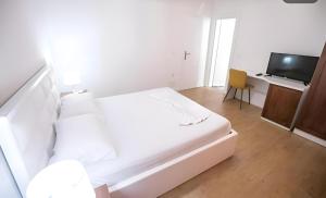a white bedroom with a bed and a television at Hotel Sidi in Tirana