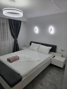 a bedroom with a large white bed and a chandelier at Sky luxury apartment in Giurgiu