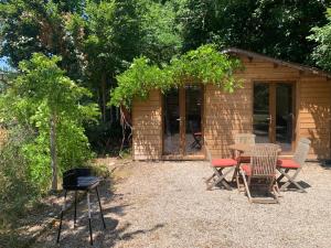 a picnic table and chairs in front of a cabin at Chalet bucolique in Saint-Étienne-de-Chigny