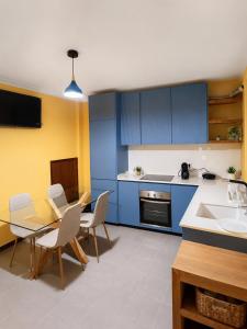 eine Küche mit blauen Schränken, einem Tisch und Stühlen in der Unterkunft Opus House in Guimarães