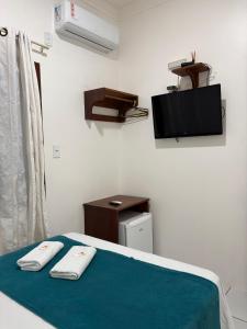 a room with a bed with a tv and towels at Pousada Vilas Boas in Barreirinhas