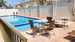 a patio with tables and chairs next to a swimming pool at Apto Completo próximo Aeroporto e Shopping in Várzea Grande