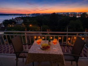 a table with a bowl of fruit on a balcony at sunset at Apartment RB in Omišalj