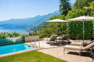a pool with chairs and umbrellas and a view of the water at Exclusive Boutique Hotel Elisabetta in Ronco sopra Ascona