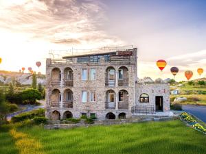 an old stone building with hot air balloons in the sky at Ala Stone Hotel - Balloon View Experience in Göreme +65 photos